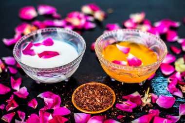 Parlak siyah ahşap yüzey üzerinde net cilt için süt yüz paketi yani çiğ süt iyi bir cam kase sandal ağacı tozu ve yüzeyde tüm ham maddeler ile karıştırılır.