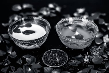 Parlak siyah ahşap yüzey üzerinde net cilt için süt yüz paketi yani çiğ süt iyi bir cam kase sandal ağacı tozu ve yüzeyde tüm ham maddeler ile karıştırılır.