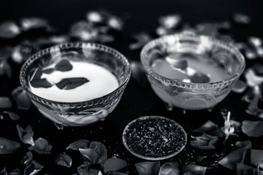 Parlak siyah ahşap yüzey üzerinde net cilt için süt yüz paketi yani çiğ süt iyi bir cam kase sandal ağacı tozu ve yüzeyde tüm ham maddeler ile karıştırılır.