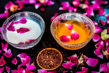 Parlak siyah ahşap yüzey üzerinde net cilt için süt yüz paketi yani çiğ süt iyi bir cam kase sandal ağacı tozu ve yüzeyde tüm ham maddeler ile karıştırılır.