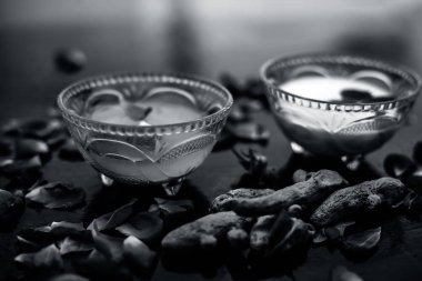 Tüm ham maddeler ile birlikte bir cam kase içinde çiğ süt, zerdeçal veya haldi ve badam oluşan siyah parlak yüzeyüzerinde Süt yüz paketi.