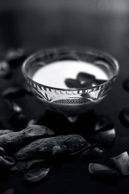 Tüm ham maddeler ile birlikte bir cam kase içinde çiğ süt, zerdeçal veya haldi ve badam oluşan siyah parlak yüzeyüzerinde Süt yüz paketi.