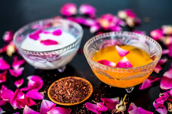 Milk face pack for clear complexion on shiny black wooden surface i.e. Raw milk well mixed with sandalwood powder in a glass bowl and entire raw ingredients on the surface.