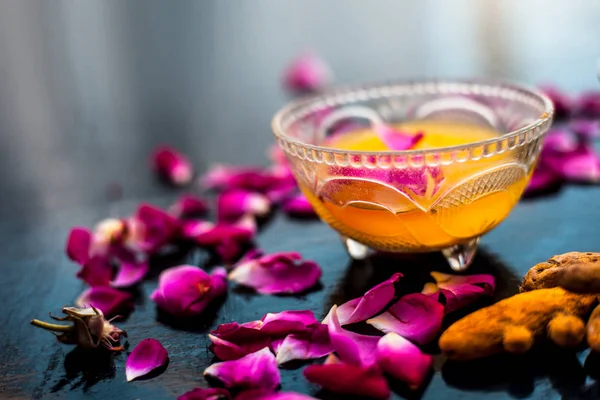 Milk face pack on black shiny surface consisting of raw milk,turmeric or haldi and badam in a glass bowl along with entire raw ingredients.