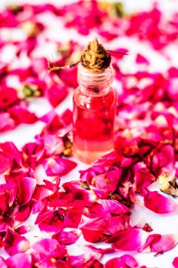 Gül yaprakları üzerinde temel gül konsantrasyonu veya özü küçük bir cam şişe ile birlikte yüzeye yayıldı.