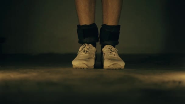 穿着白色运动鞋和黑色脚踝重量的双腿特写镜头 做跳跃运动 通过交替减轻每条腿的重量来增加身高和耐力 — 图库视频影像
