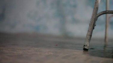 Siyah kıyafetler ve siyah ayakkabılar giyen insan bacakları da metal bir sandalyede oturuyor. Dolly atış.
