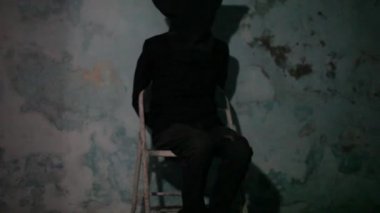 Siyah renkli bir maske ve siyah kıyafetleri giyen erkek insan elleri bağlı ve metal sandalyede oturuyor. Kidd uyuklama kavramı.