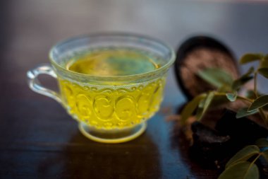 Taze gül yaprakları ve siyah renkli parlak ahşap yüzeyüzerinde hing veya Asafoetida veya Devil's gübre veya kokuşmuş sakız veya jowani badian bazı toz ile birlikte yeşil çay bir fincan.