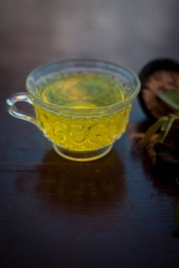 Taze gül yaprakları ve siyah renkli parlak ahşap yüzeyüzerinde hing veya Asafoetida veya Devil's gübre veya kokuşmuş sakız veya jowani badian bazı toz ile birlikte yeşil çay bir fincan.