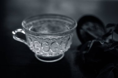 Taze gül yaprakları ve siyah renkli parlak ahşap yüzeyüzerinde hing veya Asafoetida veya Devil's gübre veya kokuşmuş sakız veya jowani badian bazı toz ile birlikte yeşil çay bir fincan.