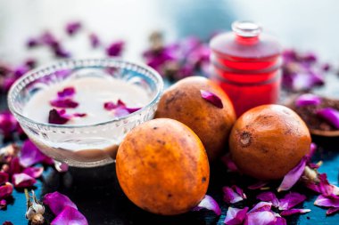 Sapodilla veya chikoo iyi içinde gül suyu kullanarak sandal ağacı ile karışık oluşan ahşap yüzey üzerinde yanaklar için yüz paketi.