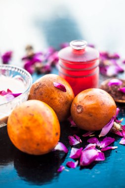 Sapodilla veya chikoo iyi içinde gül suyu kullanarak sandal ağacı ile karışık oluşan ahşap yüzey üzerinde yanaklar için yüz paketi.