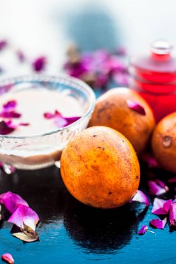 Sapodilla veya chikoo iyi içinde gül suyu kullanarak sandal ağacı ile karışık oluşan ahşap yüzey üzerinde yanaklar için yüz paketi.