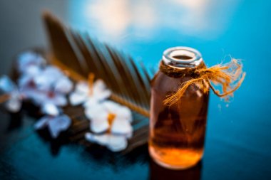 Biberiye konsantrasyonu veya özü, çiçekleri ve bazı yaprakları ile birlikte ahşap yüzeyüzerinde bir cam şişe.