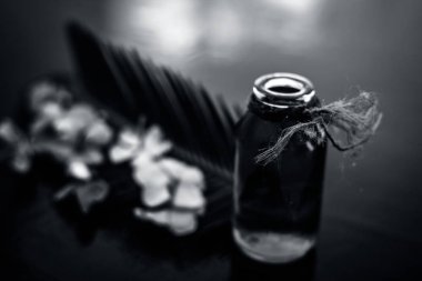 Biberiye konsantrasyonu veya özü, çiçekleri ve bazı yaprakları ile birlikte ahşap yüzeyüzerinde bir cam şişe.