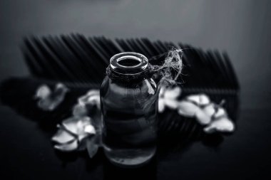 Biberiye konsantrasyonu veya özü, çiçekleri ve bazı yaprakları ile birlikte ahşap yüzeyüzerinde bir cam şişe.