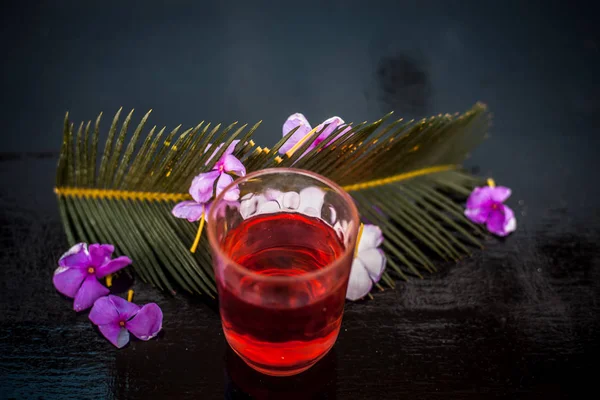 在木质表面的玻璃杯中萃取迷迭香花 以及迷迭香花和叶子 — 图库照片