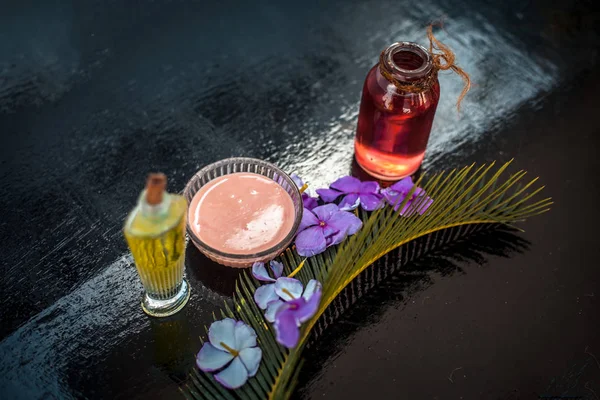 Hair treatment for long thick hairs on wooden surface i.e. Rosemary essential oil well mixed with olive oil in a glass bowl and some rosemary flowers also.