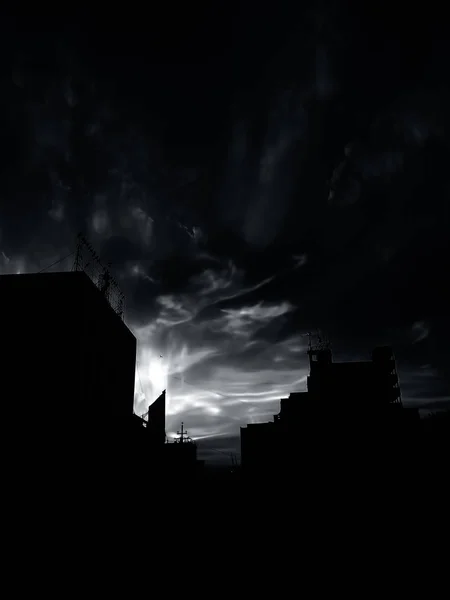建物のいくつかのシルエットと一緒に背景に雲と太陽の夕暮れ時間ショットも — ストック写真