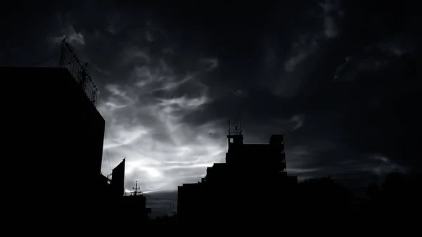 建物のいくつかのシルエットと一緒に背景に雲と太陽の夕暮れ時間ショットも — ストック写真