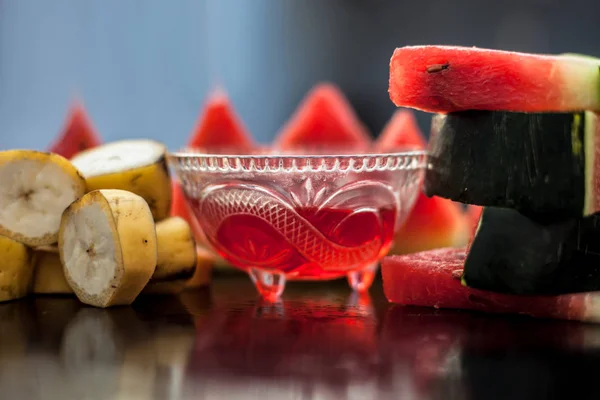 Watermelon face mask or face pack on wooden surface in a glass bowl along with watermelon pieces cut in triangle shape consisting of watermelon and banana.Used for instant natural glow.