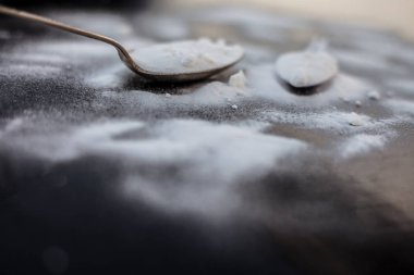 Ham toz kabartma tozu ahşap yüzeyüzerinde antika bir kaşık la birlikte plastik bir kaşık biraz daha. Yatay atış.