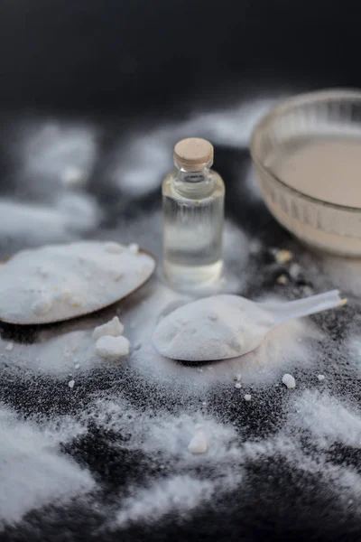 Face mask or face pack of baking soda in a glass bowl on wooden surface along with powder and some coconut oil in a transparent glass bottle. Used for rashes. Vertical shot.