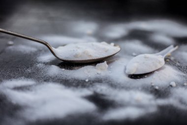 Ham toz kabartma tozu ahşap yüzeyüzerinde antika bir kaşık la birlikte plastik bir kaşık biraz daha. Yatay ve üst atış.