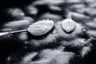 Ham toz kabartma tozu ahşap yüzeyüzerinde antika bir kaşık la birlikte plastik bir kaşık biraz daha. Yatay ve üst atış.