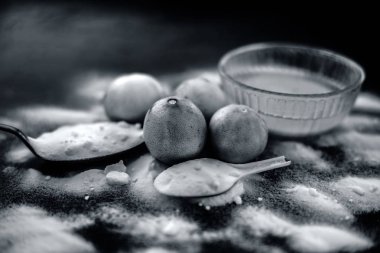 Kabartma tozu yüz maskesi ahşap yüzeyüzerinde cam bir kapta bazı kabartma tozu ile birlikte yüzeye serpilir ve limon da yüzeyde. Deriyi anında lekeler. Yatay atış.