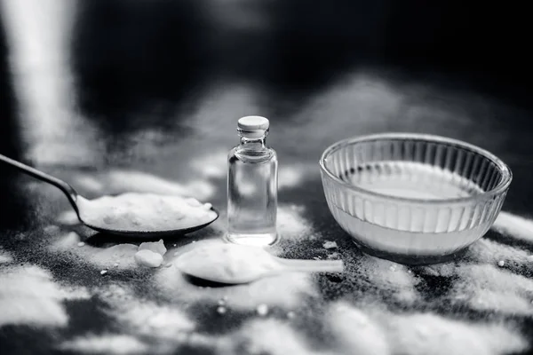 Face mask or face pack of baking soda in a glass bowl on wooden surface along with powder and some coconut oil in a transparent glass bottle. Used for rashes. Horizontal shot.