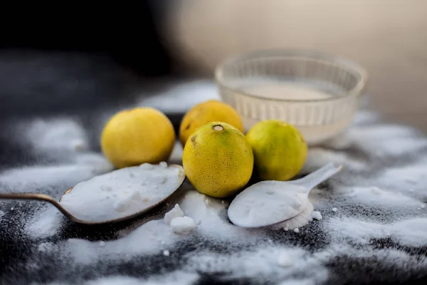 Baking soda face mask in a glass bowl on wooden surface along with some baking soda sprinkled on the surface and lemons also on surface. Used to blemishes skin instantly.Horizontal shot.