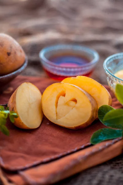 Potato juice\'s face pack or face mask in a glass bowl on jute bag\'s surface consisting of potato juice and honey.Used for skin whitening purpose along with entire ingredients.Vertical low angle shot.