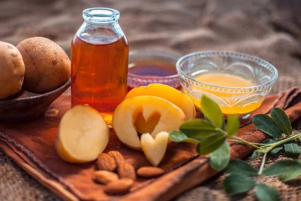 Glowing face mask of potato juice in a glass bowl on brown colored surface along with some Potato juice,honey and almond oil.Horizontal shot.To eliminate skin rashes, remove impurities,etc.