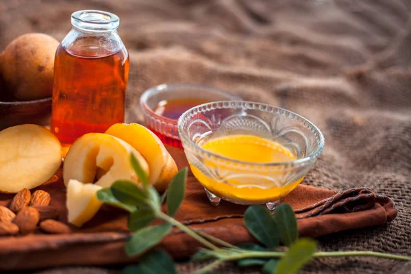 Glowing face mask of potato juice in a glass bowl on brown colored surface along with some Potato juice,honey and almond oil.Horizontal shot.To eliminate skin rashes, remove impurities,etc.