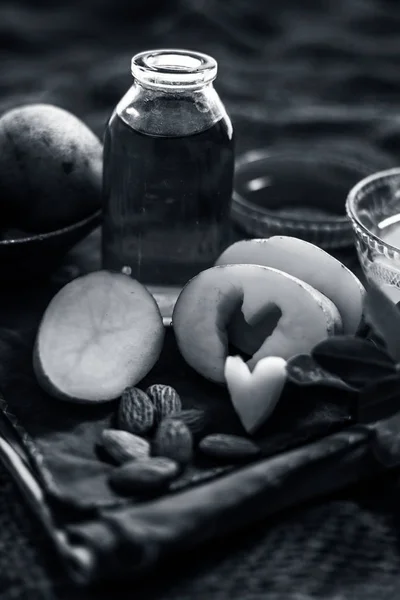 Glowing face mask of potato juice in a glass bowl on brown colored surface along with some Potato juice,honey and almond oil.Horizontal shot.To eliminate skin rashes, remove impurities,etc.