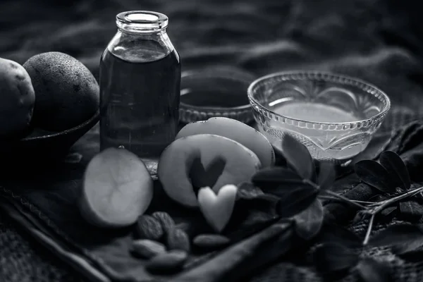 Glowing face mask of potato juice in a glass bowl on brown colored surface along with some Potato juice,honey and almond oil.Horizontal shot.To eliminate skin rashes, remove impurities,etc.