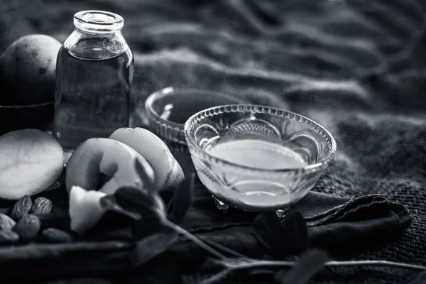 Glowing face mask of potato juice in a glass bowl on brown colored surface along with some Potato juice,honey and almond oil.Horizontal shot.To eliminate skin rashes, remove impurities,etc.