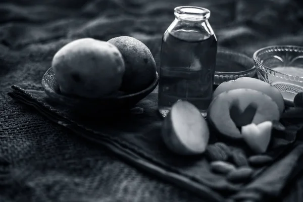 Glowing face mask of potato juice in a glass bowl on brown colored surface along with some Potato juice,honey and almond oil.Horizontal shot.To eliminate skin rashes, remove impurities,etc.