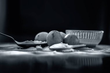 Kabartma tozu yüz maskesi ahşap yüzeyüzerinde cam bir kapta bazı kabartma tozu ile birlikte yüzeye serpilir ve limon da yüzeyde. Deriyi anında lekeler. Yatay atış.