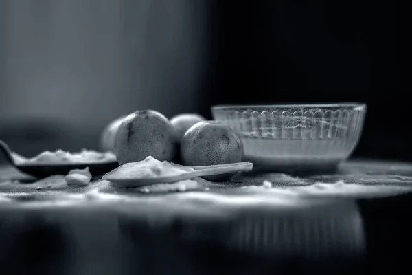 Baking soda face mask in a glass bowl on wooden surface along with some baking soda sprinkled on the surface and lemons also on surface. Used to blemishes skin instantly.Horizontal shot.