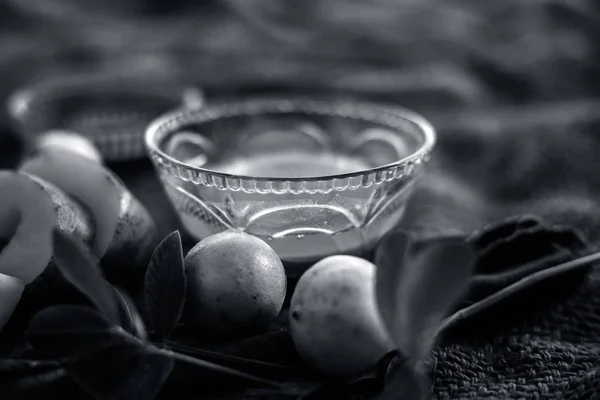 Glowing face mask of potato juice in a glass bowl on brown colored surface along with some lemon juice,potato juice and honey.Horizontal shot.