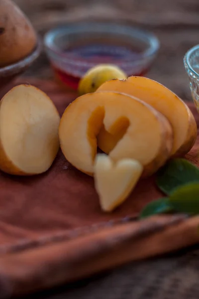 Glowing face mask of potato juice in a glass bowl on brown colored surface along with some lemon juice,potato juice and honey.Horizontal shot.