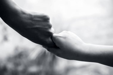 Olgunlaşmış adamın elini tutan kadın çocuğun eli, bulanık arka plan ile vuruldu. Babalar Günü konsepti. Erkekler engelleri ve korkuları fethetmek için kadın el yardımcı olur. Yatay atış.