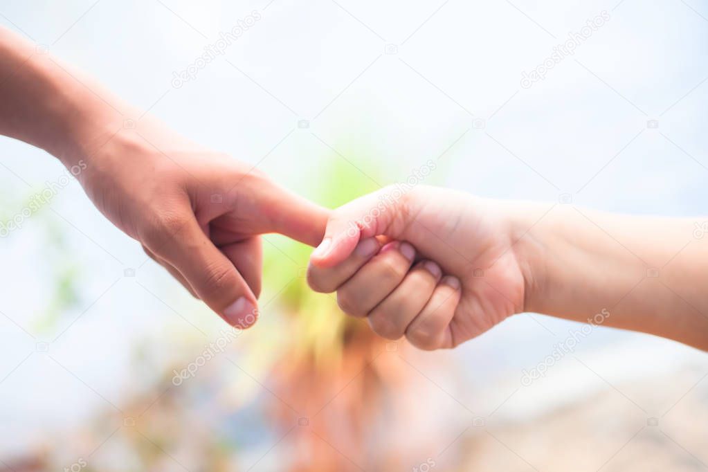 Hand of female child holding the hand of matured man, Shot with blurred background. Concept of Father's day. Men helping the female hand to overcome conquer obstacles and fears. Horizontal shot.