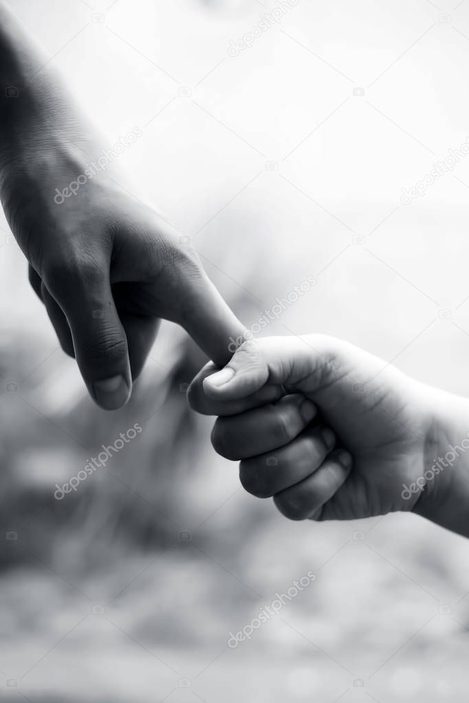 Hand of female child holding the hand of matured man, Shot with blurred background. Concept of Father's day. Men helping the female hand to overcome conquer obstacles and fears. Vertical shot.