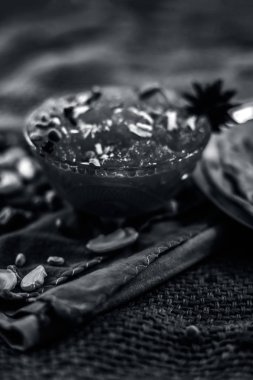 Ünlü mango koruma yani Murba veya Murabba jüt çanta yüzey üzerinde bir cam kase kuru meyve ve baharat ile birlikte. Arka plan bulanık olan dikey çekim.