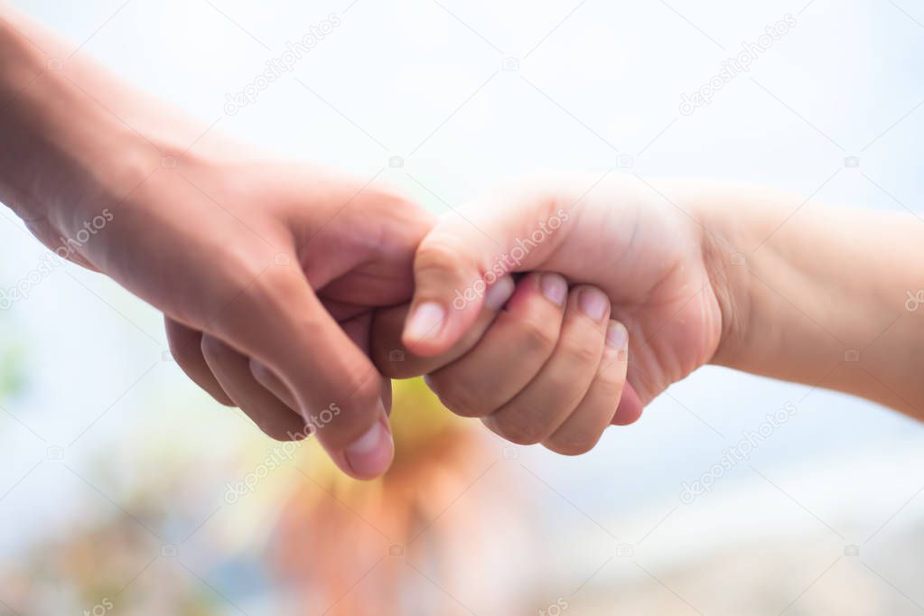 Close up shot of two hands one of father and daughter with blurred background. Concept of Fathers day and taking care of female child, Helping to conquer fear and obstacles in practical life.