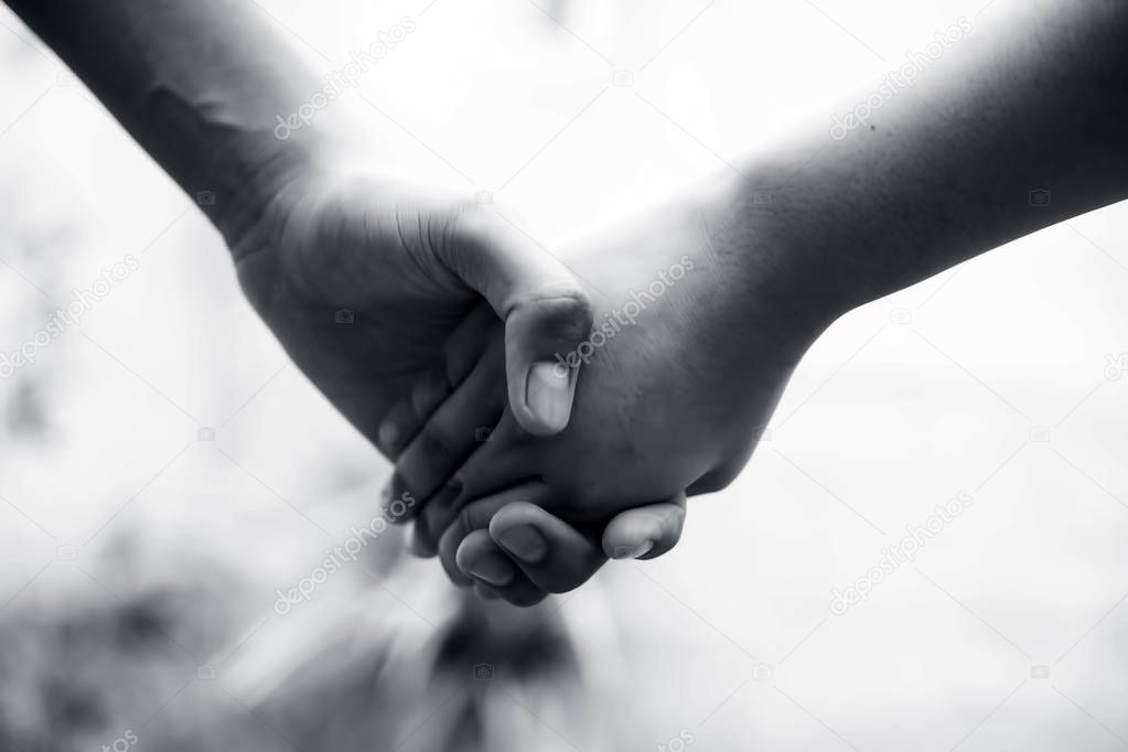 Female childs hand holding the hand of elder male shot with bokeh background and horizontal. Concept of fathers day 16th June.